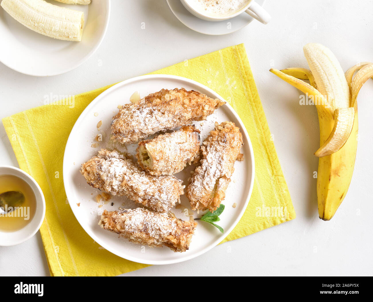 Deep fried bananas on plate over white stone background. Tasty dessert