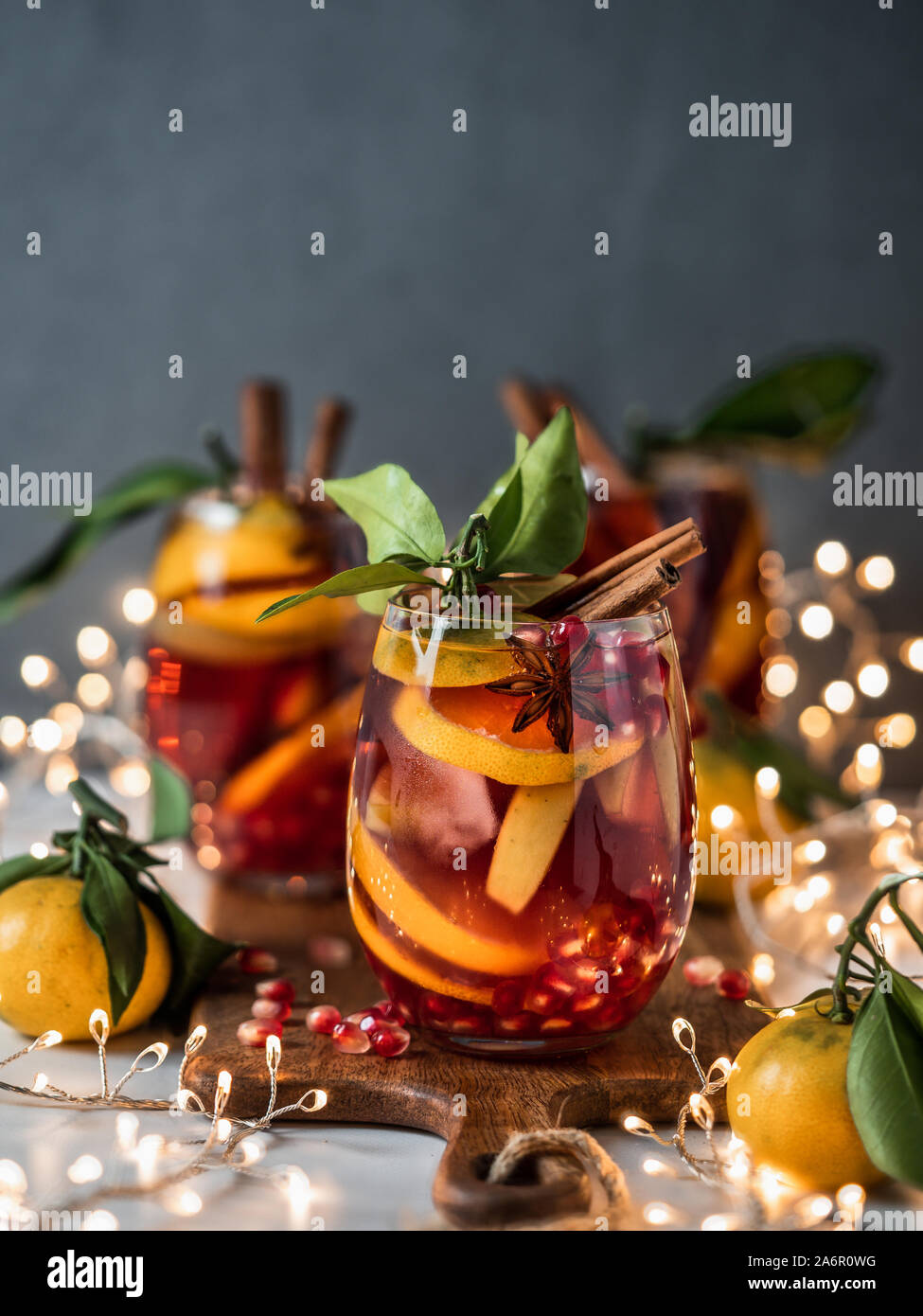 Winter sangria on dark christmas holiday background. Jugful of sangria and glasses with fruit slice, pomegranate and spices. Copy space for text or design. Vertical. Stock Photo