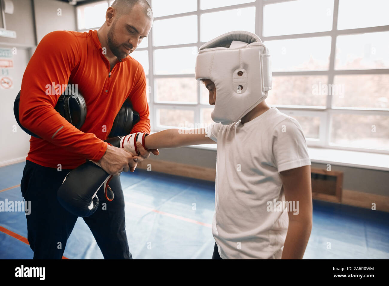 trainer putting sport gear on the boy before training, close up side view photo Stock Photo