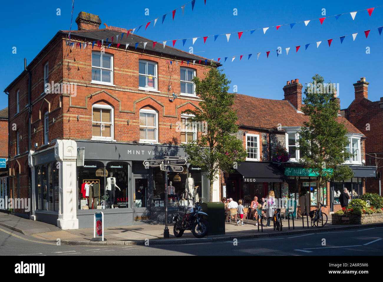 Marlow High Street in Buckinghamshire with shops, cafes and bunting across the street with a clear blue sky Stock Photo