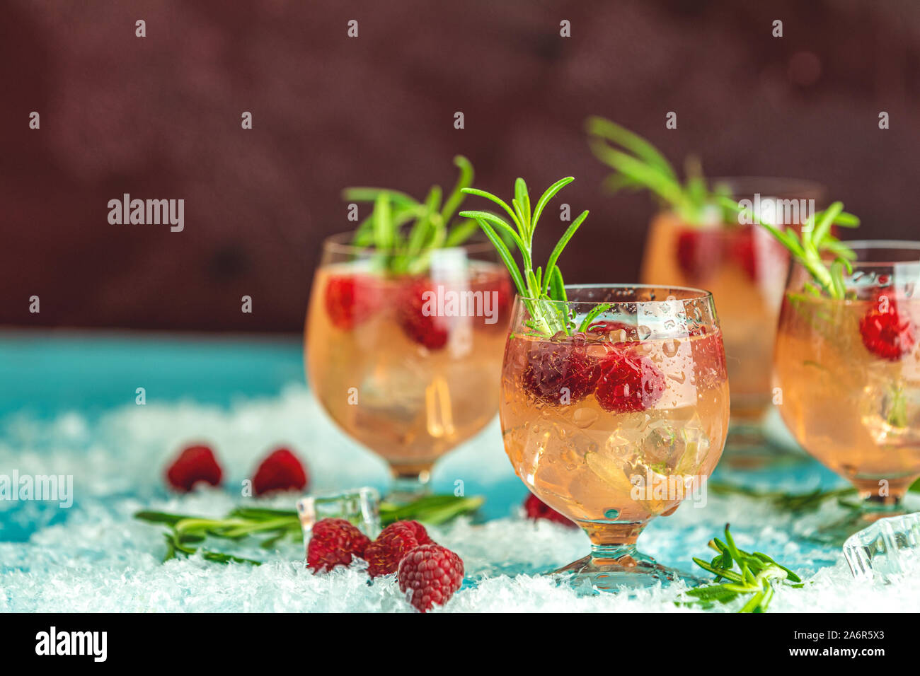 Fresh raspberry cocktail with rosemary and ice in glasses with water