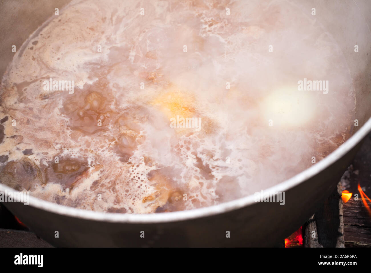 Boiling hot broth with beef and vegetables is in a cauldron. Preparing