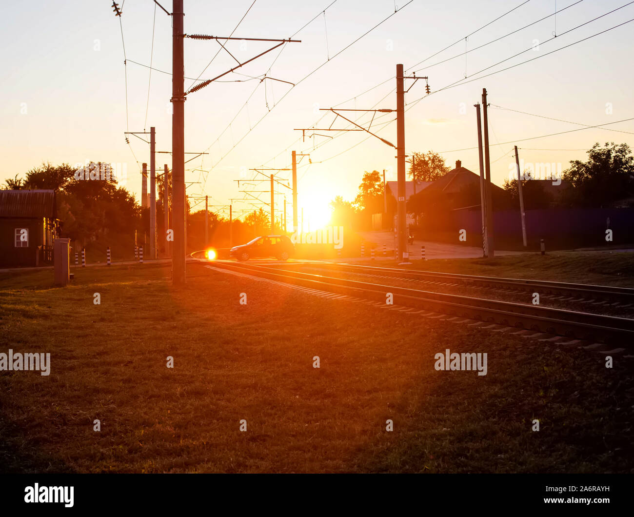 Railroad crossing on which cars ride in the background of the sun. Rail accident concept involving road transport, copy space, damage Stock Photo