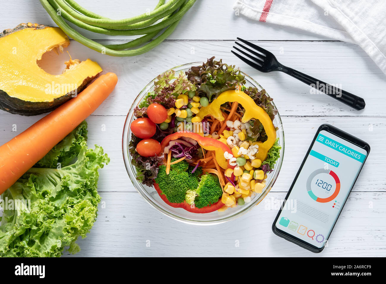 Calories counting , diet , food control and weight loss concept. Calorie counter application on smartphone screen at dining table with salad, fruit ju Stock Photo