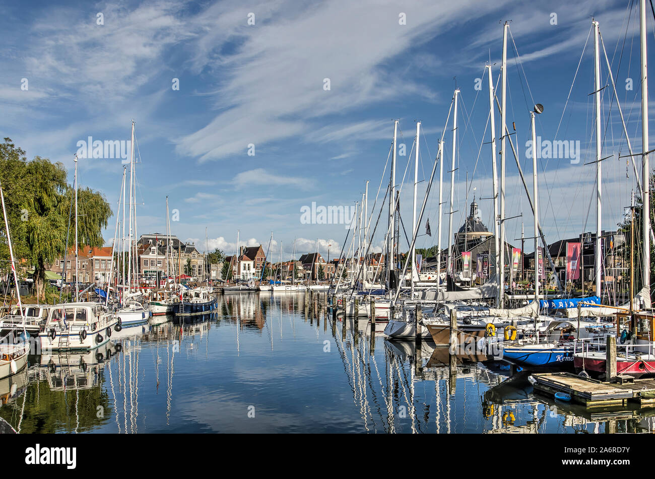 Enkhuizen, The Netherlands, September 13, 2019: blue sky, modern yachts and historic facades reflect in the mirror-like water of the inner harbour mar Stock Photo