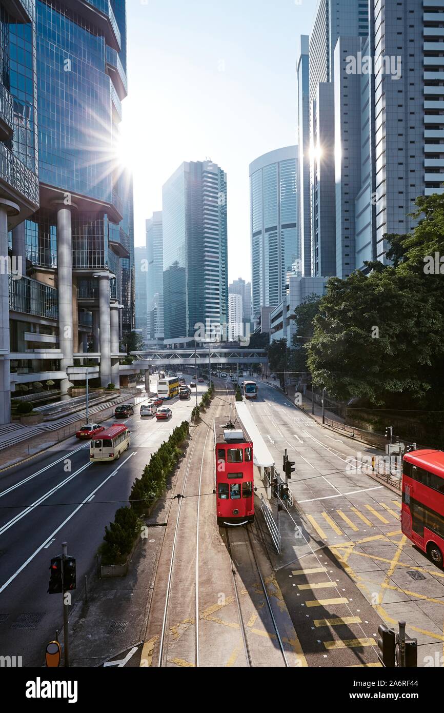 Red double-decker tram on city street against skyscrapers. Traffic in downtown financial area in Hong Kong, China. Stock Photo