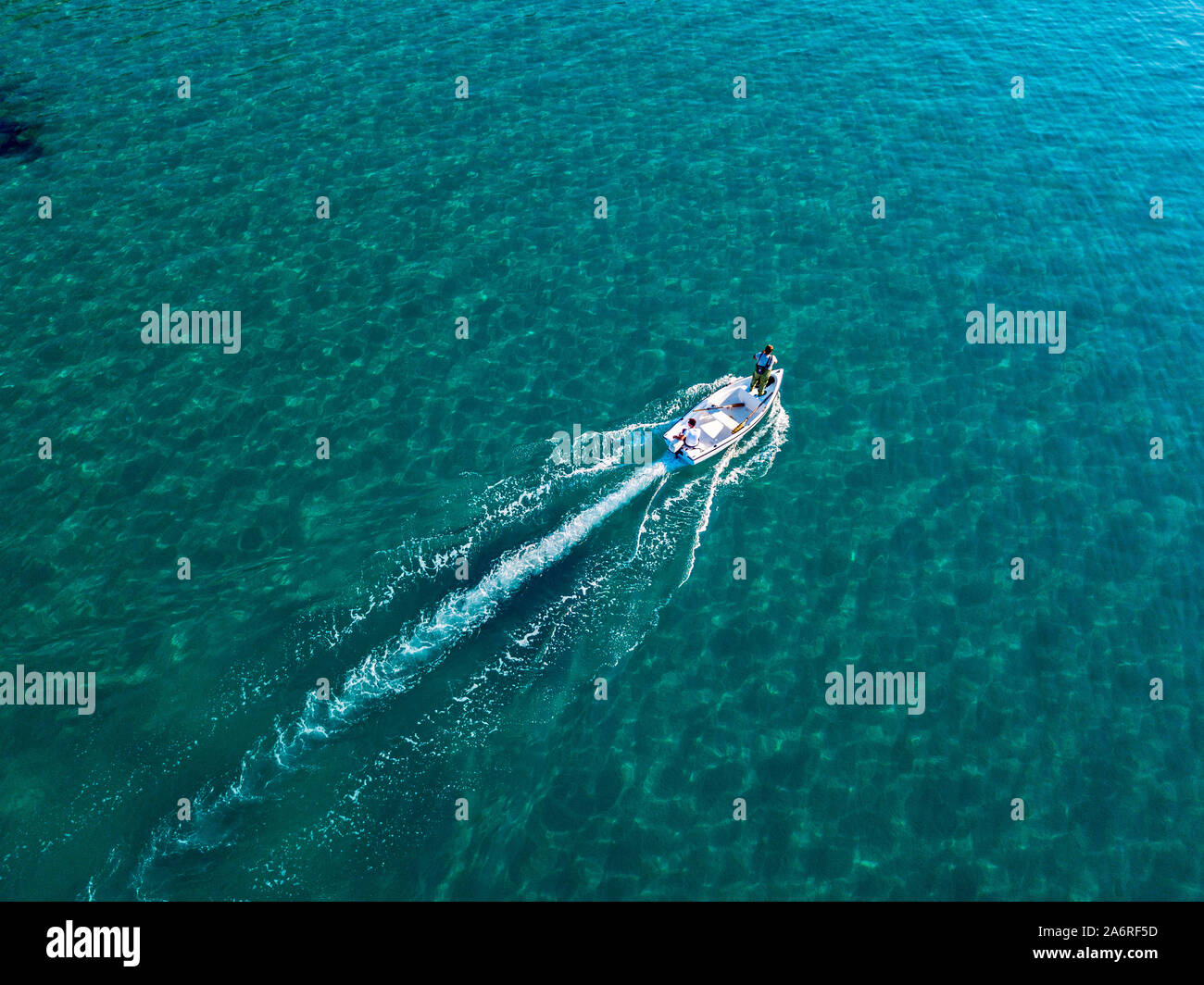 Aerial view of a rowing boat seen from above, powered by an engine. Blue sea that surrounds a boat that crosses it. People inside a boat. 10/22/2019 Stock Photo