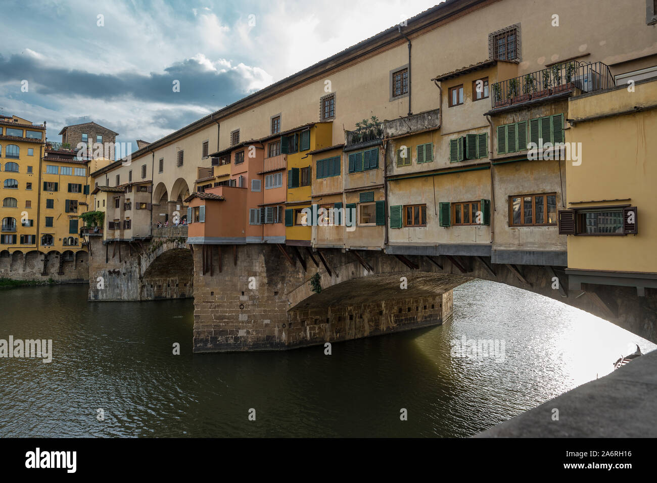 Side view of medieval stone bridge Ponte Vecchio over the Arno River in Florence, Tuscany, Italy. View from the Lungarno degli Archibusieri. Florence is a popular tourist destination of Europe. Stock Photo