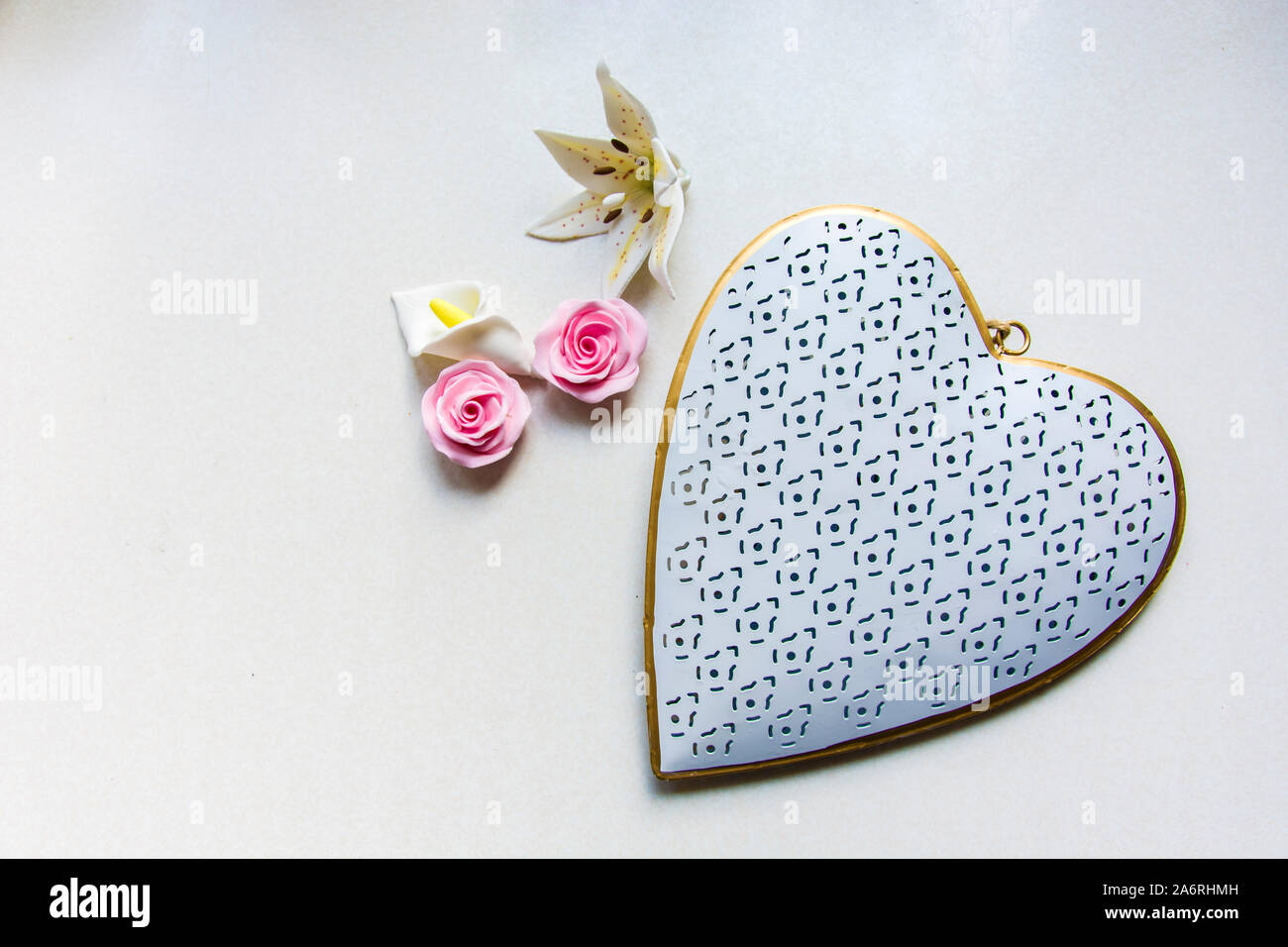 White-gold heart pendant and flowers with sugar on the background Stock Photo