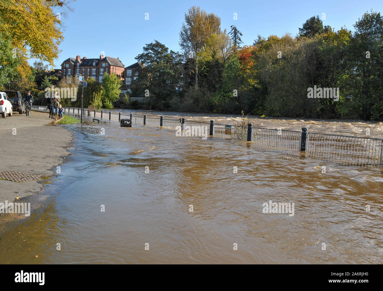 People looking over the swollen river at The Weir in Shrewsbury after recent heavy rain cause flooding in Shropshire, UK Stock Photo