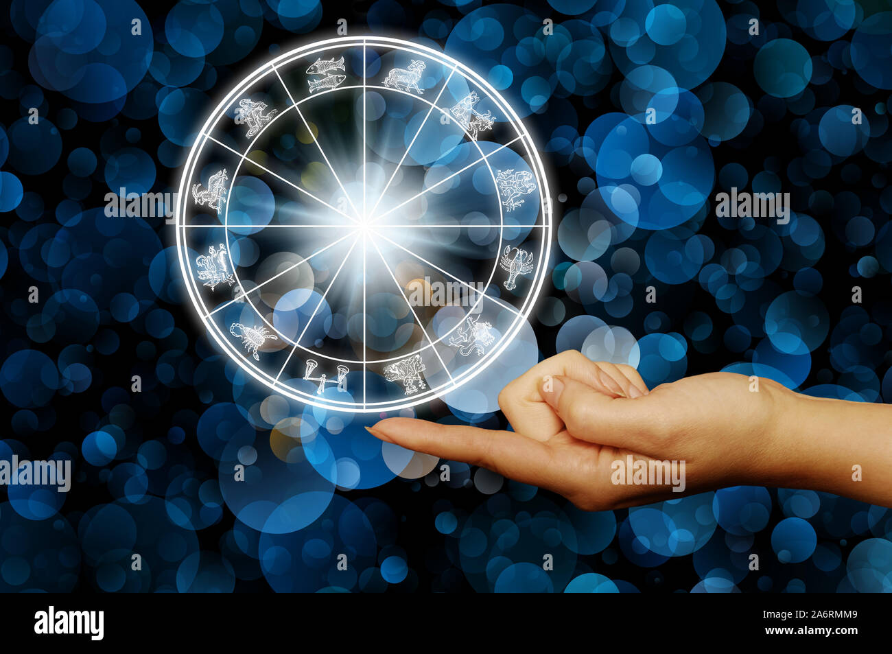 finger holding an astrology wheel with zodiac signs Stock Photo
