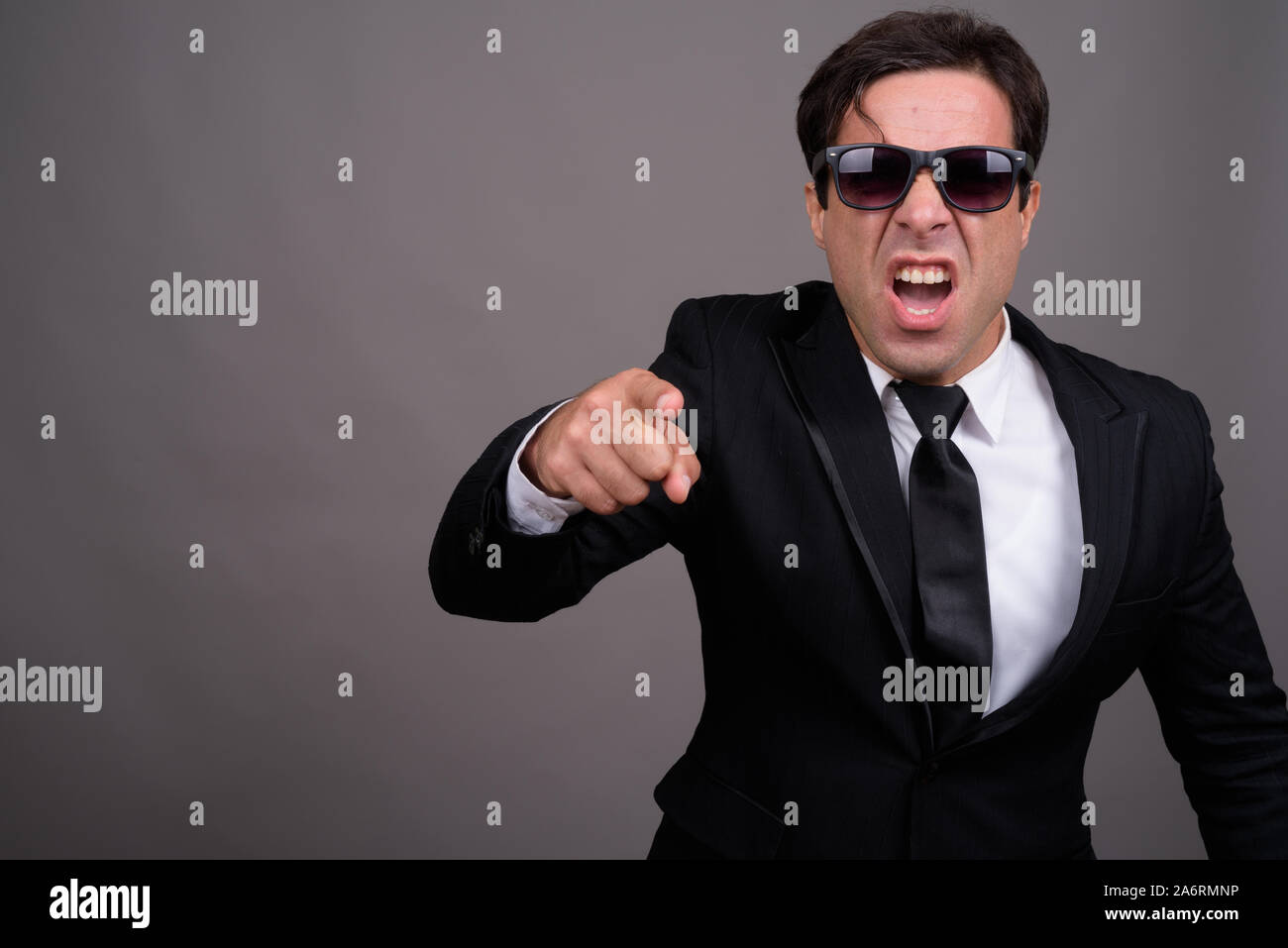 Angry Persian businessman with sunglasses pointing at camera Stock Photo