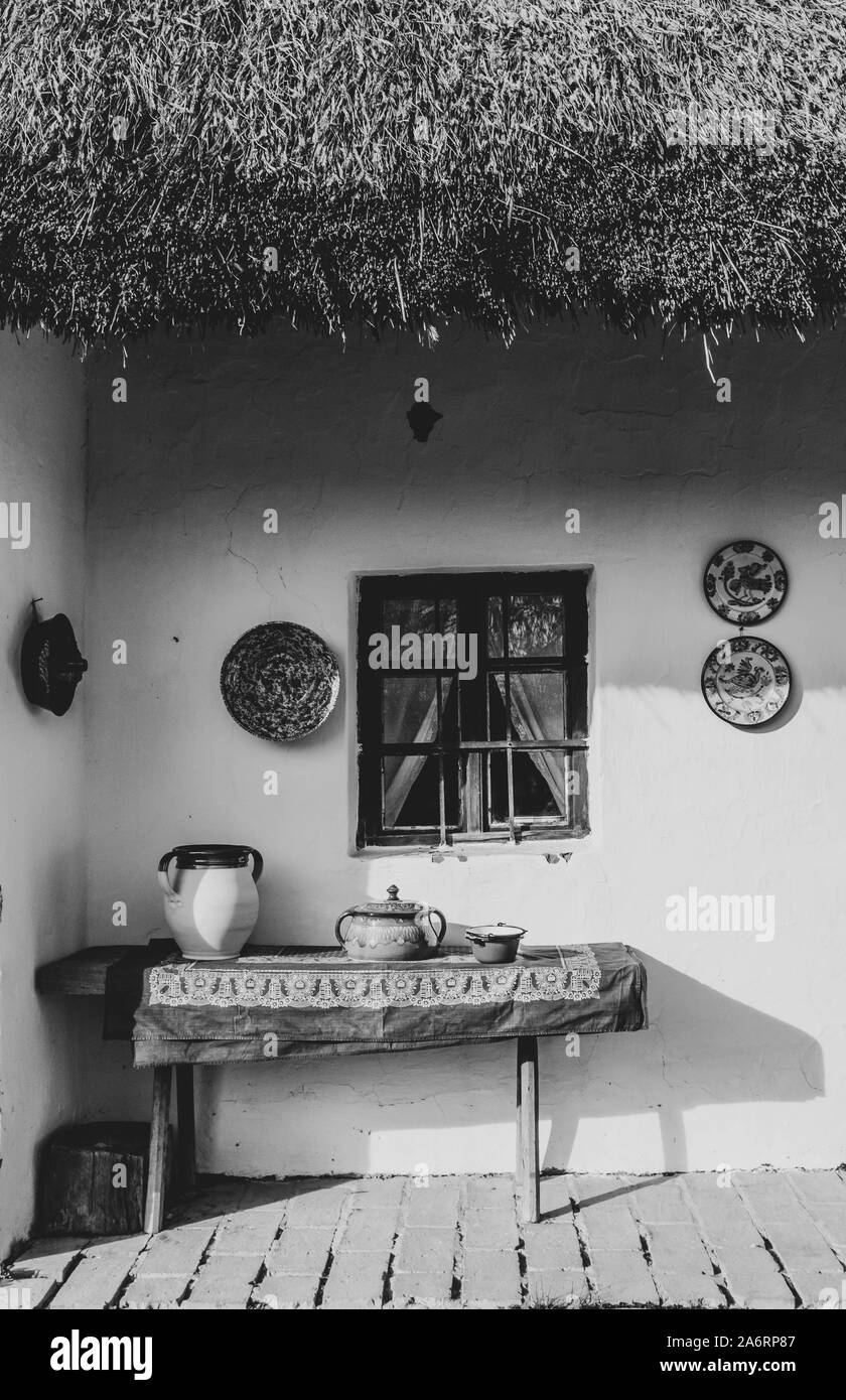 Black and white photo of exposition of pottery near traditional Hungarian house in Szentendre Skanzen Village Museum. Stock Photo