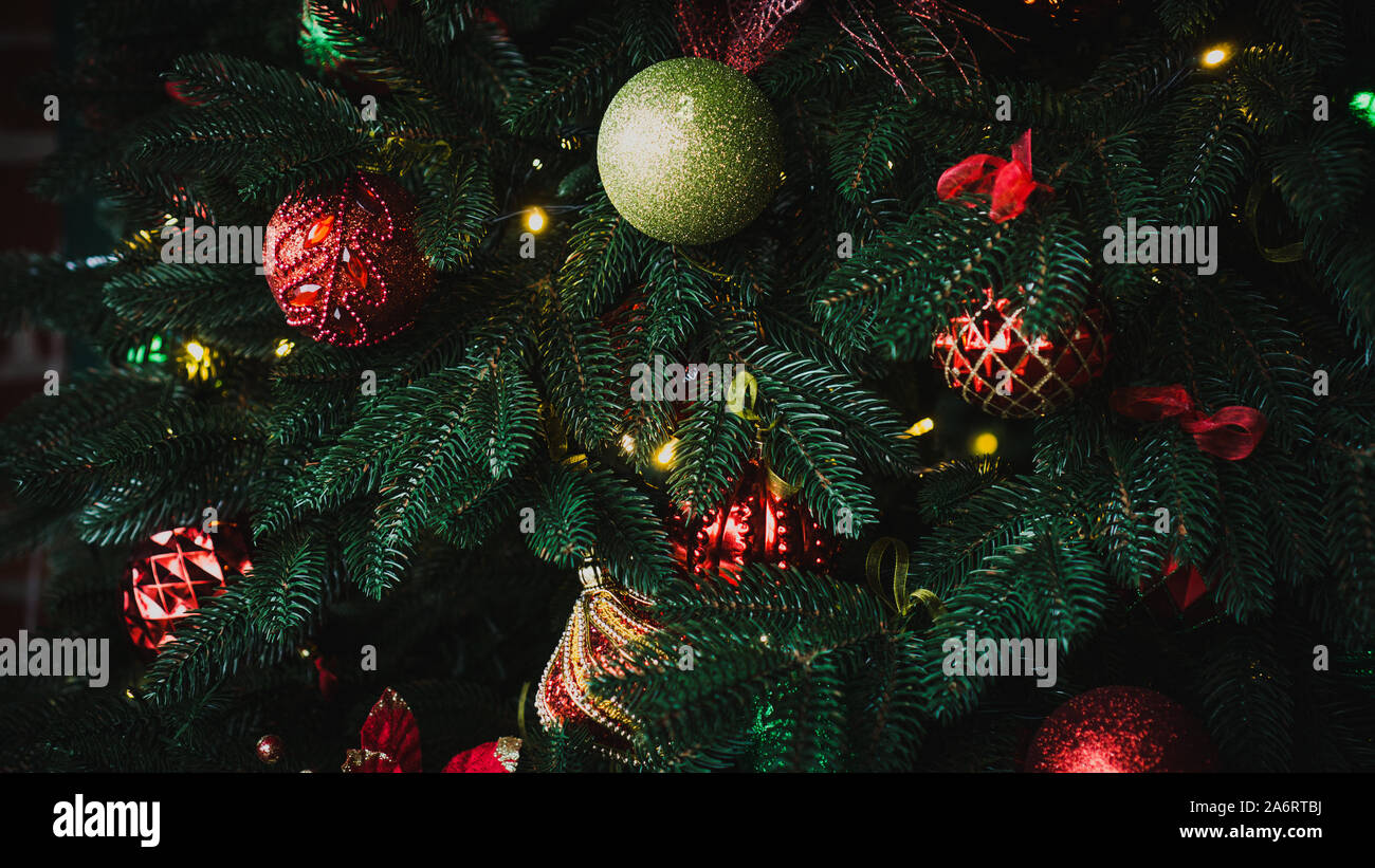 New Year's red and green shiny balls hanging on a fir branch. Lights and garlands. Christmas and happy new year concept, winter holiday light decorati Stock Photo