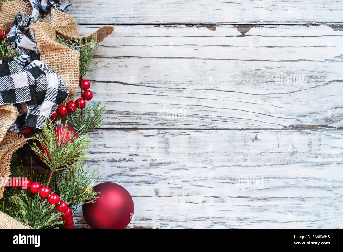 Christmas background with holiday trimmings of pine tree branches, ornaments, black and white buffalo check ribbon, burlap and red bead garland.. Top Stock Photo