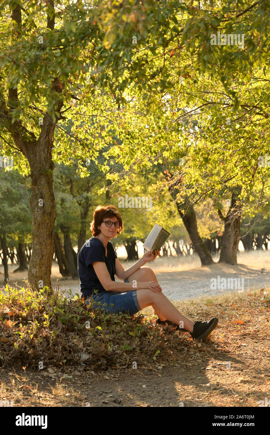 Woman reading a book in autumn forest Stock Photo