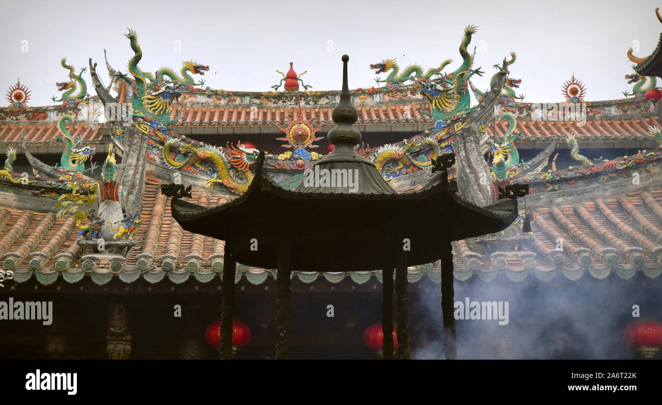 Incense burning with smoke coming up and densely adorned roofs with dozens of dragons at the Tonghuai Guanyue temple of Chinese native religion in Qua Stock Photo