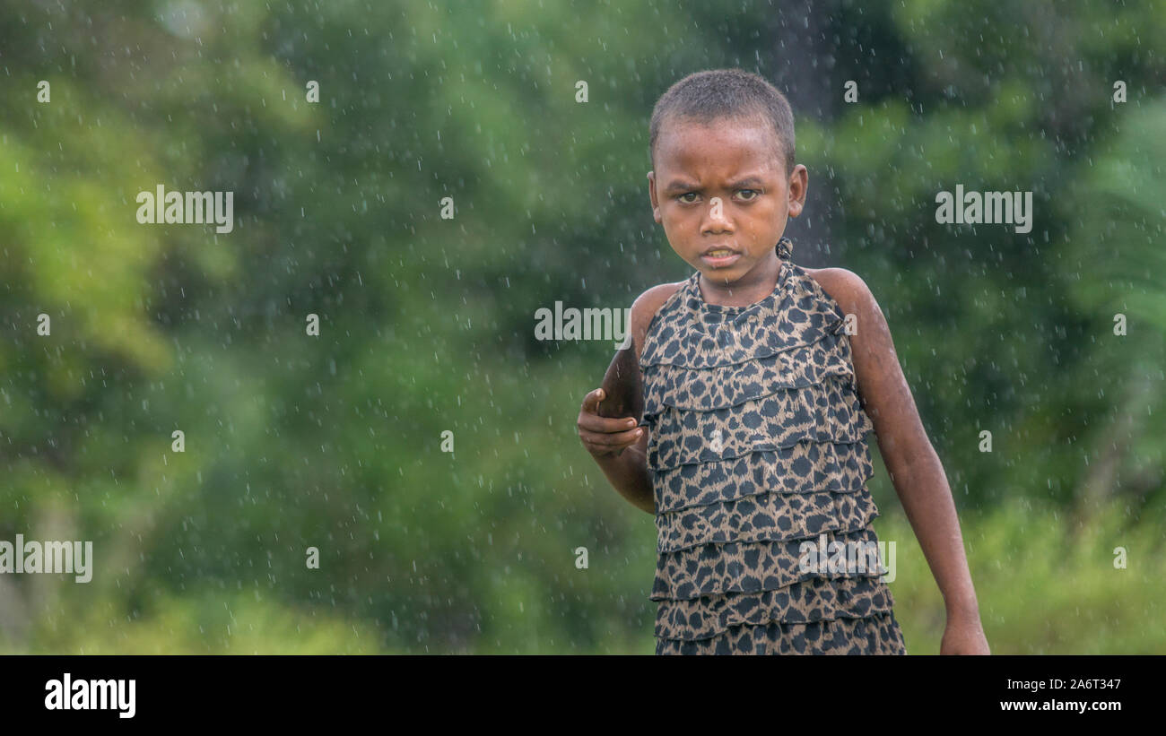 Young girl trying to sell a handicraft dugout under the rain, Pangalanes canal, Madagascar Stock Photo