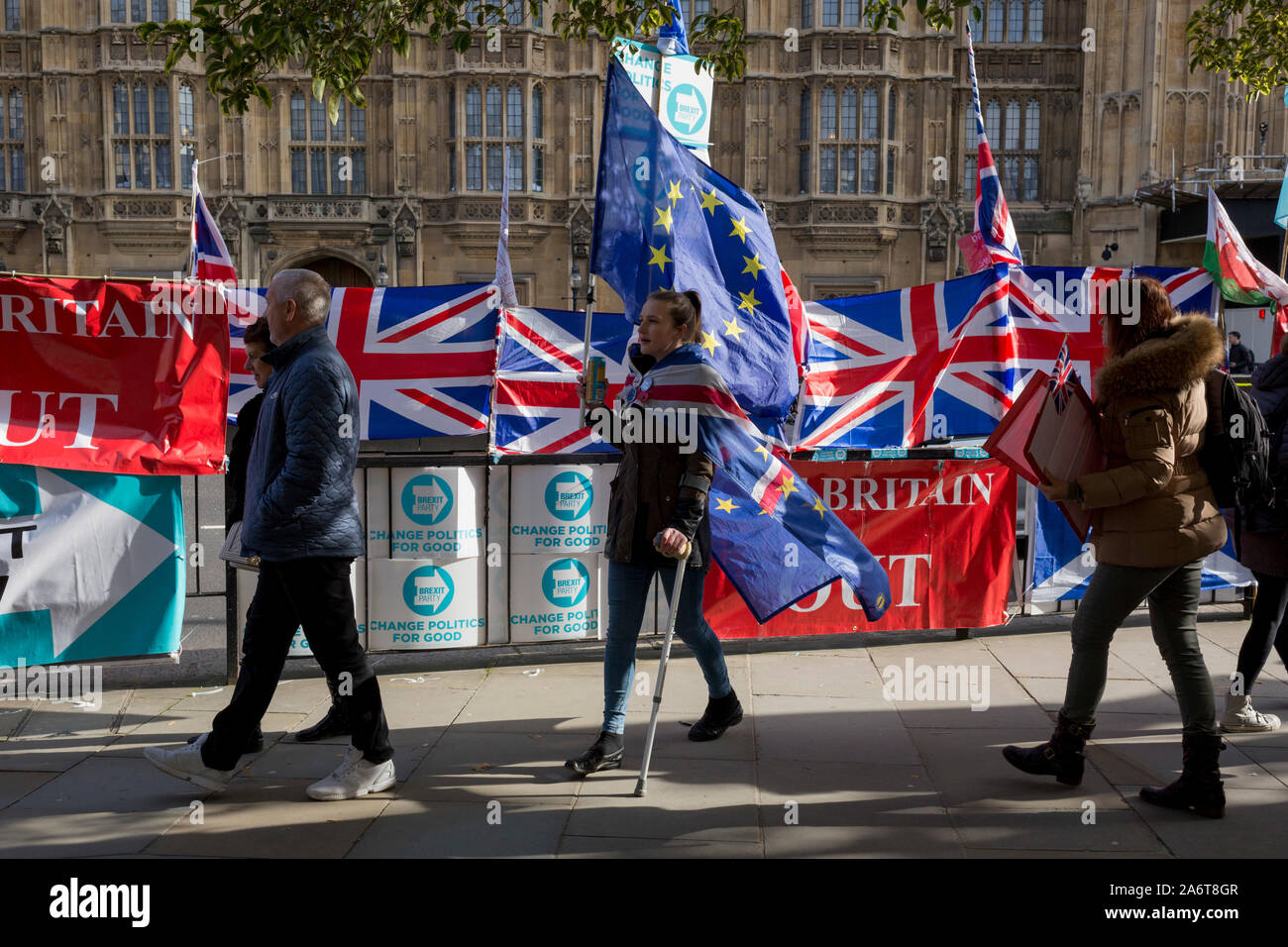 On the day that the EU in Brussels agreed in principle to extend Brexit until 31st January 2020 (aka 'Flextension') and not 31st October 2019, a Remainer lady carries an EU flag past Brexit Party flags and banners during a Brexit protest outside parliament, on 28th October 2019, in Westminster, London, England. Stock Photo