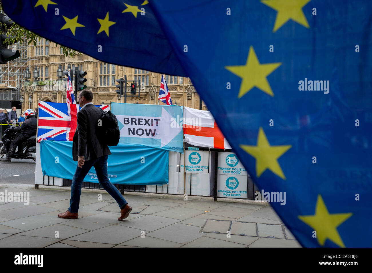 On the day that the EU in Brussels agreed in principle to extend Brexit until 31st January 2020 (aka 'Flextension') and not 31st October 2019, a pedestrian walks past Brexit Party flags and banners during a Brexit protest outside parliament, on 28th October 2019, in Westminster, London, England. Stock Photo