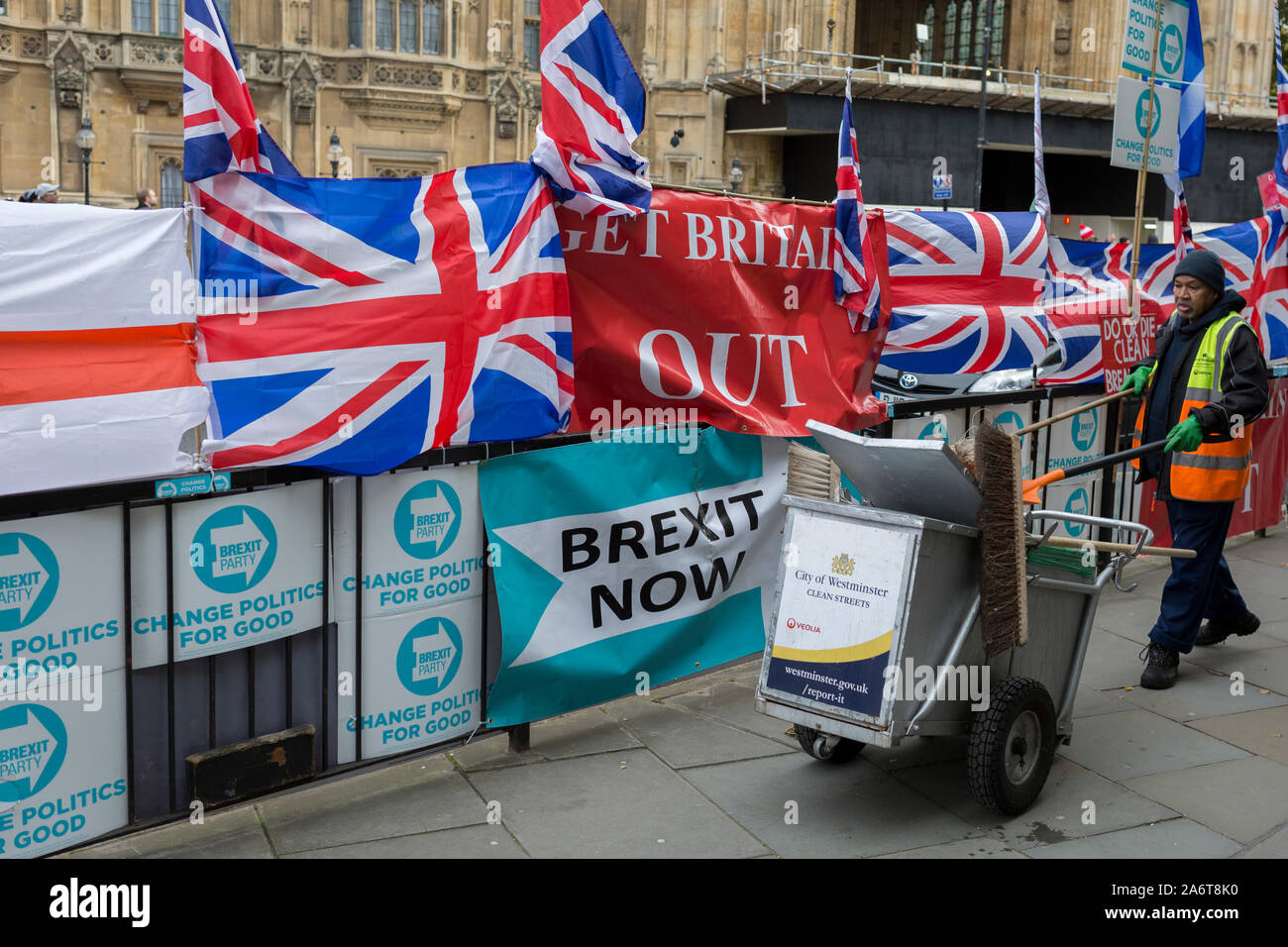 On the day that the EU in Brussels agreed in principle to extend Brexit until 31st January 2020 (aka 'Flextension') and not 31st October 2019, a Westminster borough street cleaner picks up litter next to Brexit Party flags and banners during a Brexit protest outside parliament, on 28th October 2019, in Westminster, London, England. Stock Photo
