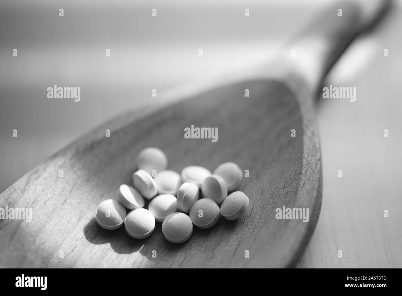 Medical pills in a wooden spoon closeup. Black and white poto Stock