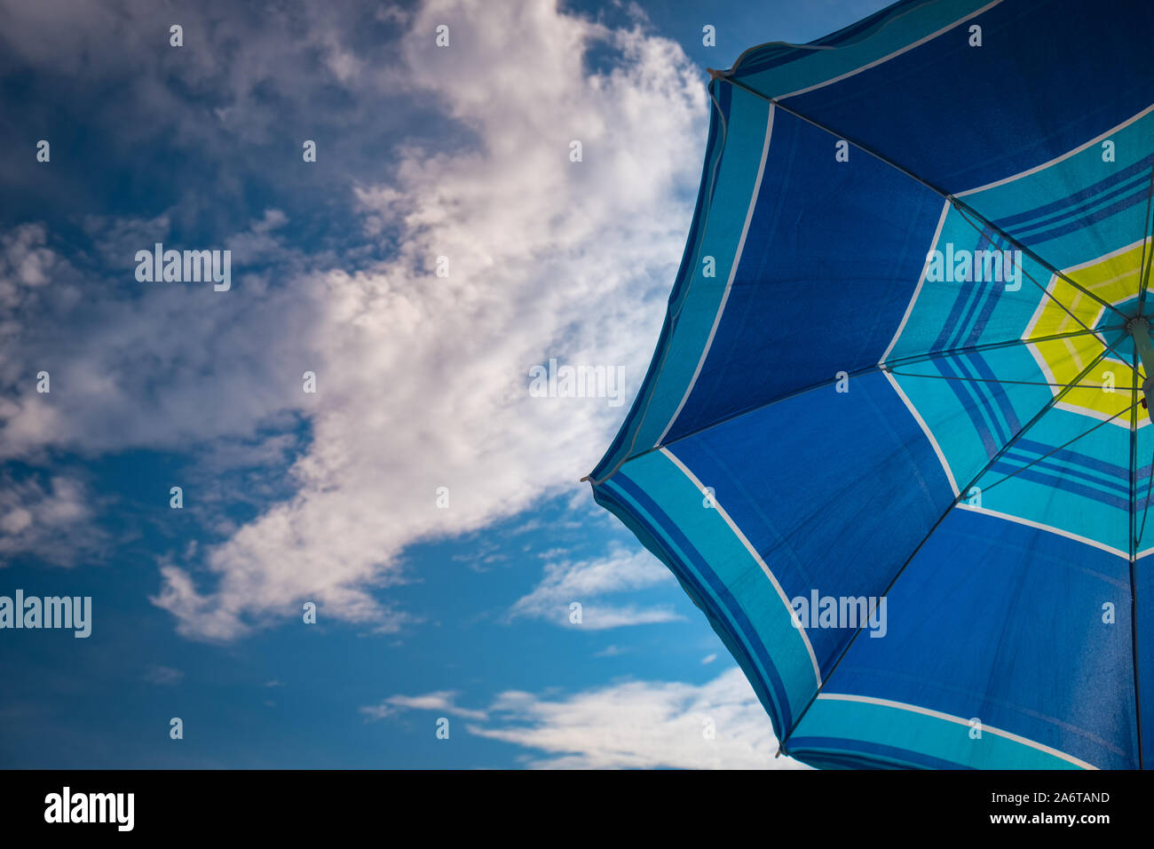 Blue parasol on the blue sky background. Summer vacation background