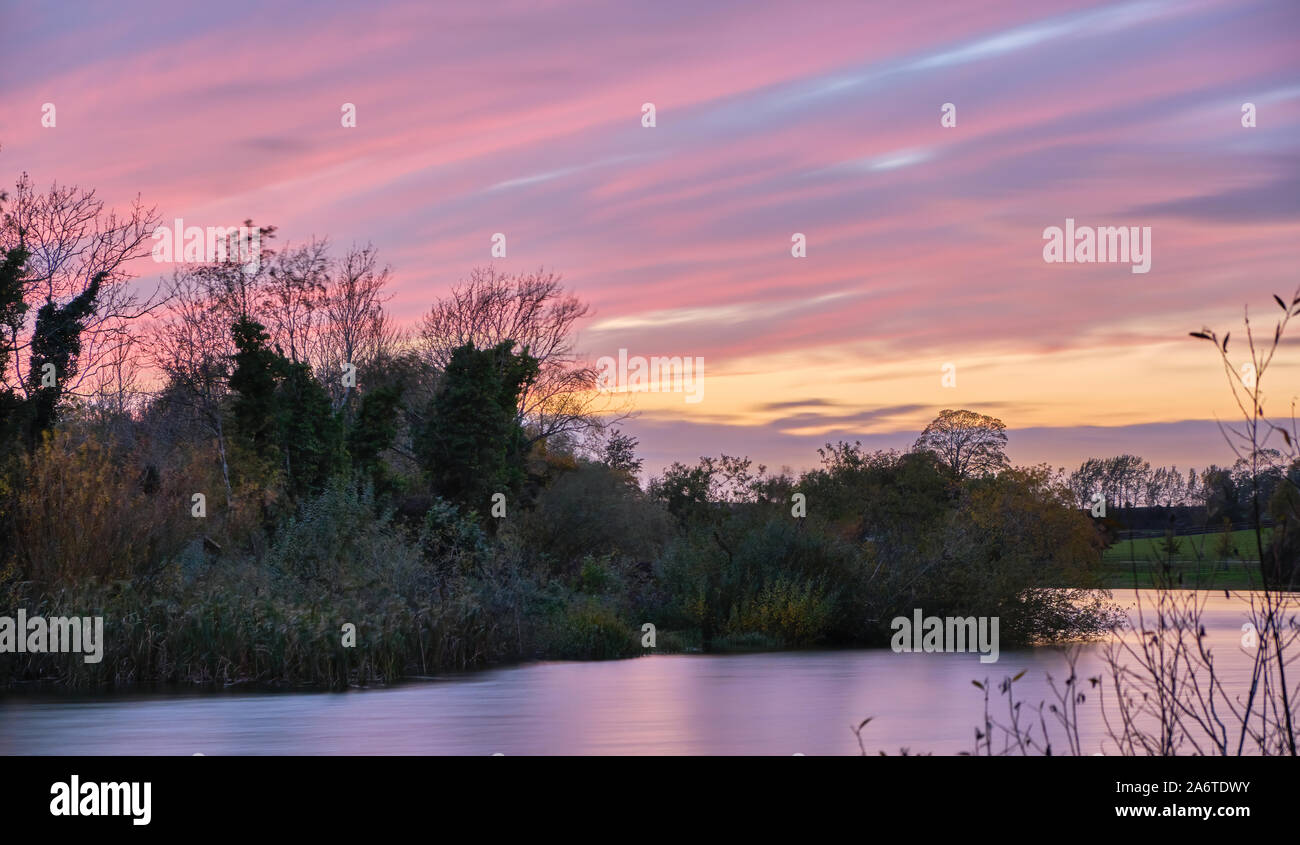 Autumnal sunset with reflections over a tree lined Culverthorpe Lake in the Lincolnshire rural countryside Stock Photo