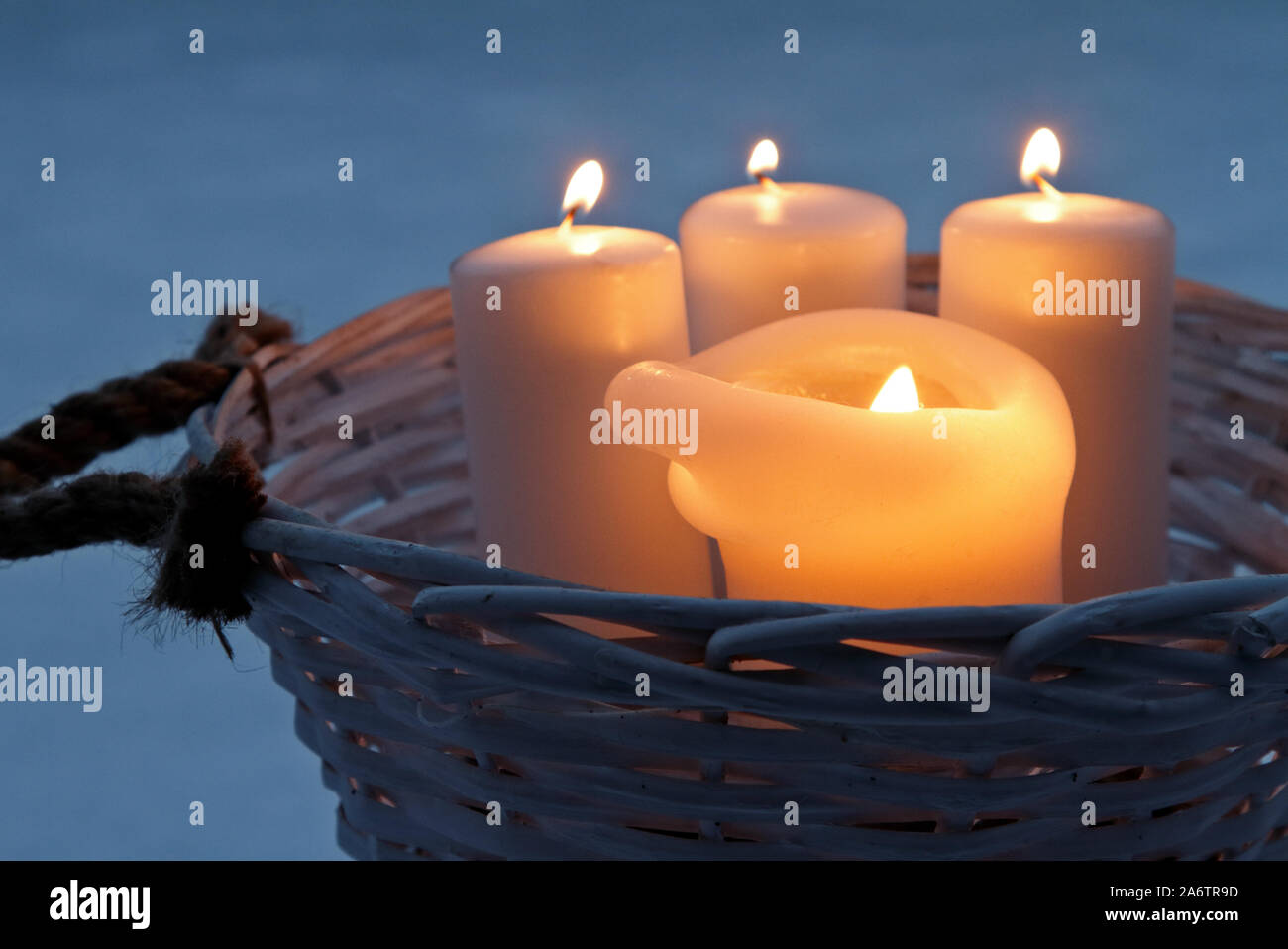 White candles burning outdoors in a rattan basket Stock Photo Alamy