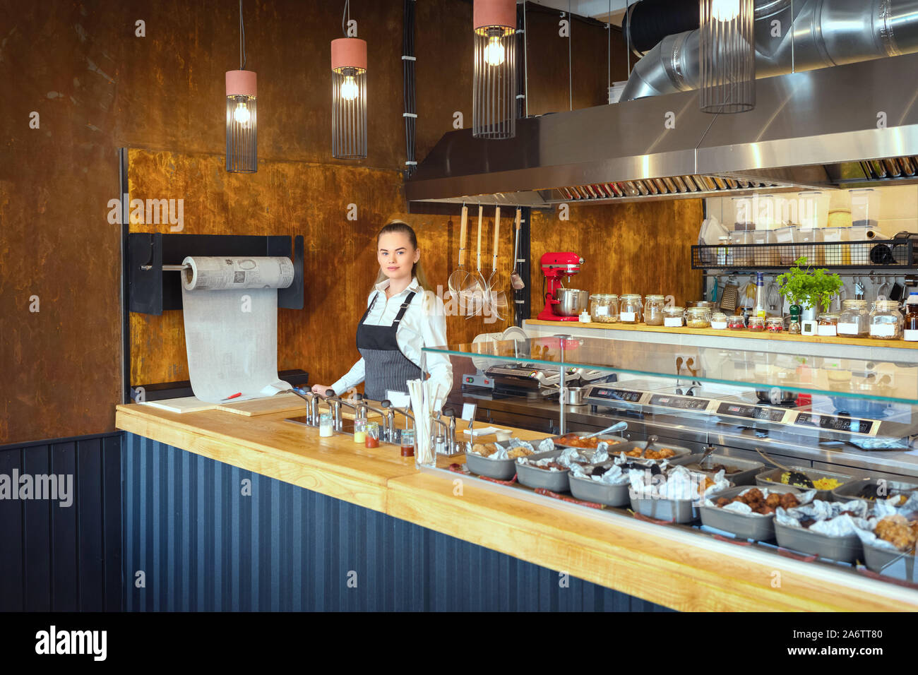 Successful small business owner looking at camera while standing behind counter in eatery Stock Photo