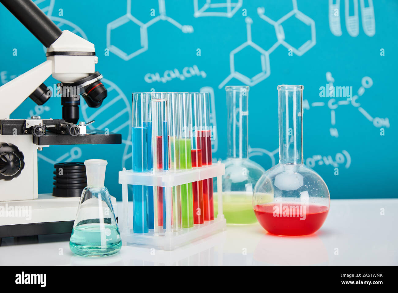microscope, glass test tubes and flasks with colorful liquid on blue ...