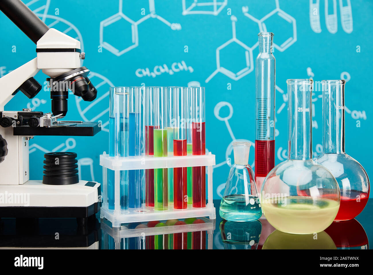 microscope, glass test tubes and flasks with colorful liquid on blue ...