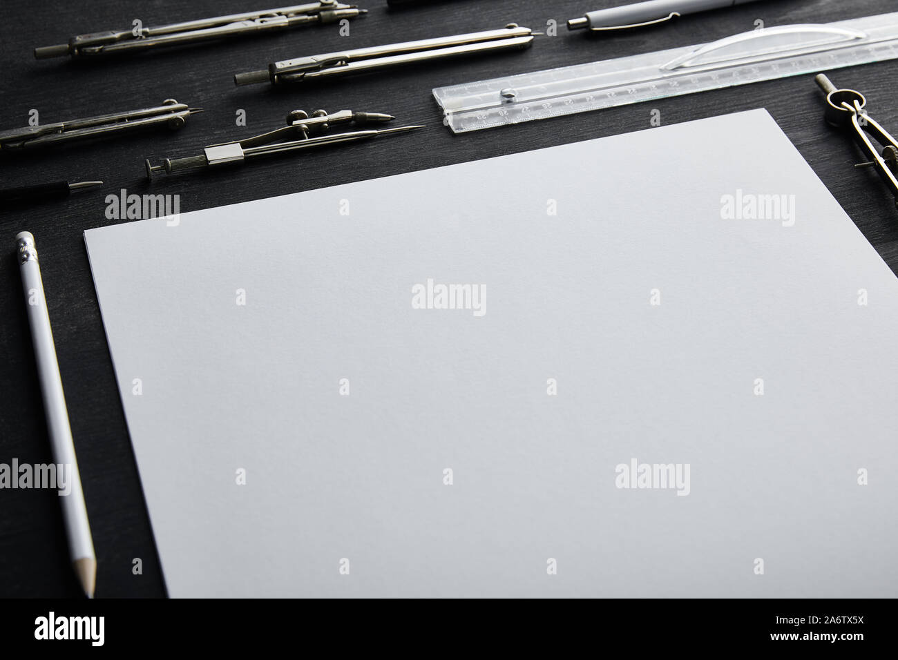 white paper with copy space and compasses, ruler, pencil, pen on black and wooden table Stock Photo