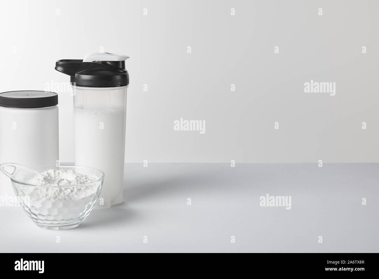 https://c8.alamy.com/comp/2A6TX8R/sports-bottle-with-protein-shake-near-jar-and-protein-powder-on-white-2A6TX8R.jpg