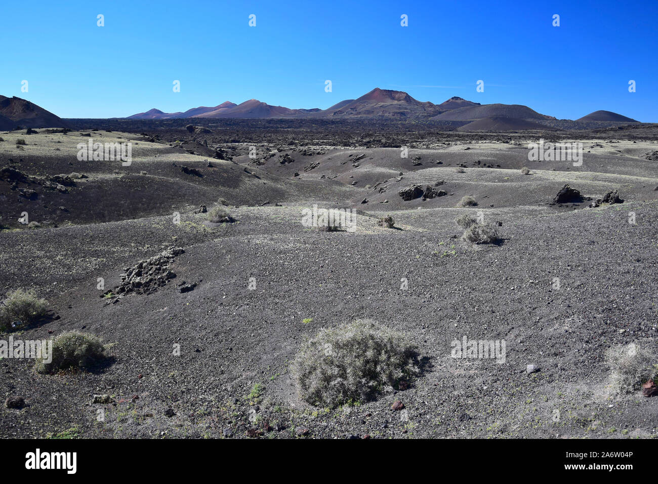 A barren landscape in Lanzarote with the volcanos of the Timanfaya national park in the back. Stock Photo