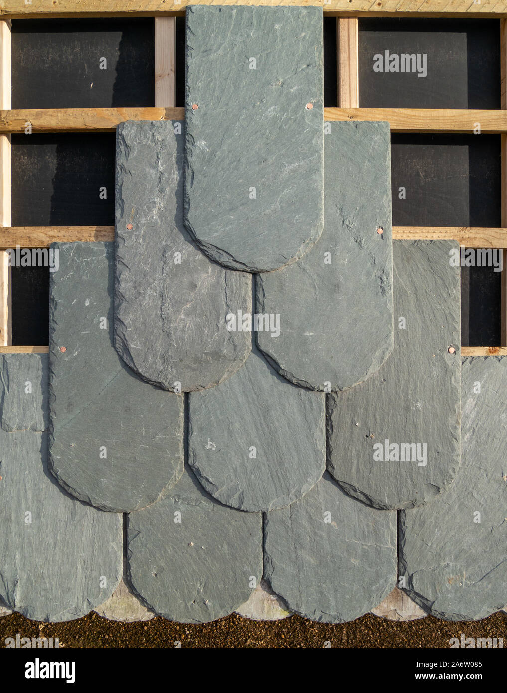 Closeup showing construction of nailed slate tiled roof with felt, tiles and wooden roofing laths / battens. Stock Photo