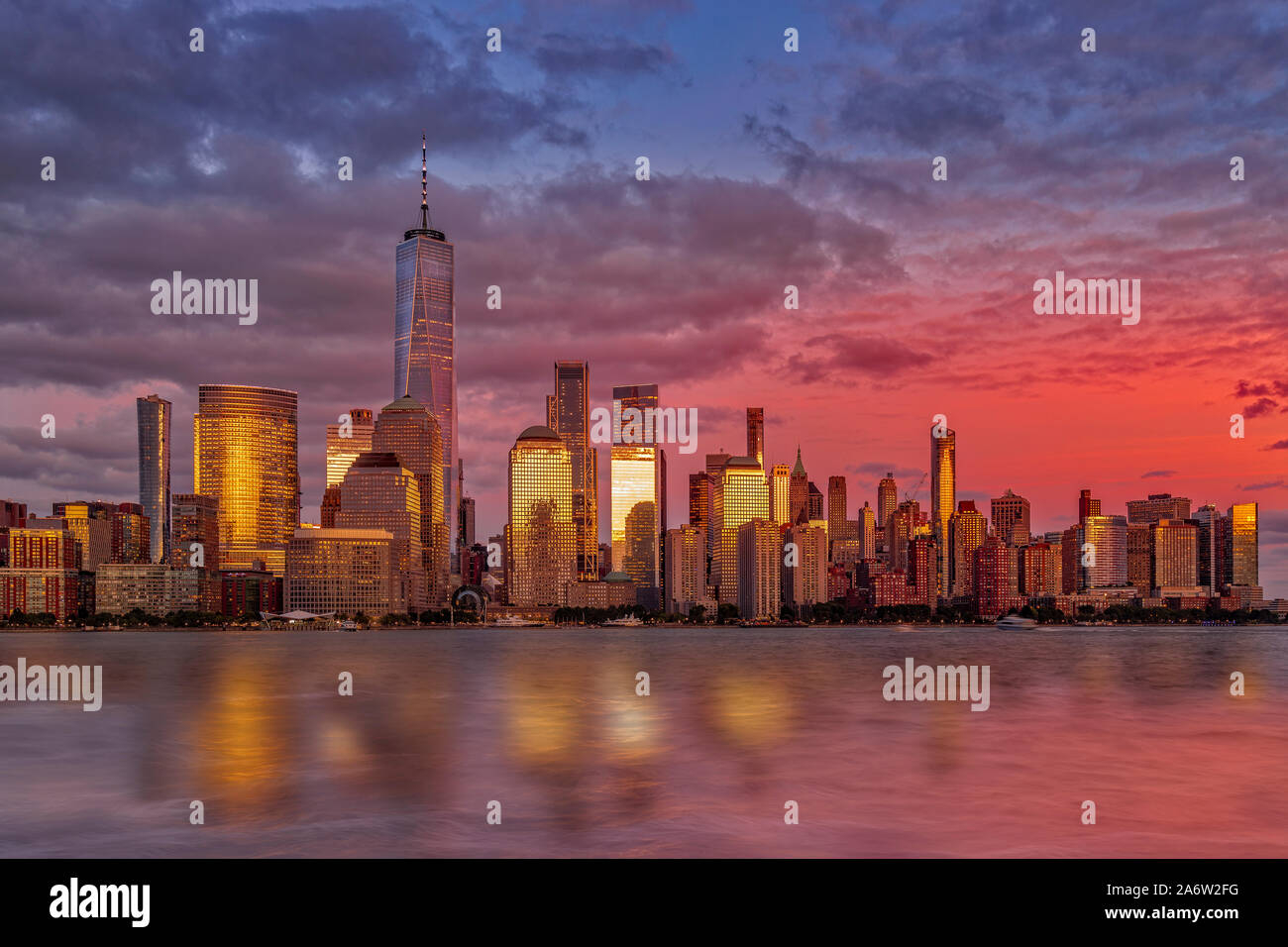 NYC Skyline Sundown - The sun sets by One World Trade Center, coined the Freedom Tower in the lower Manhattan skyline in New York City. Stock Photo