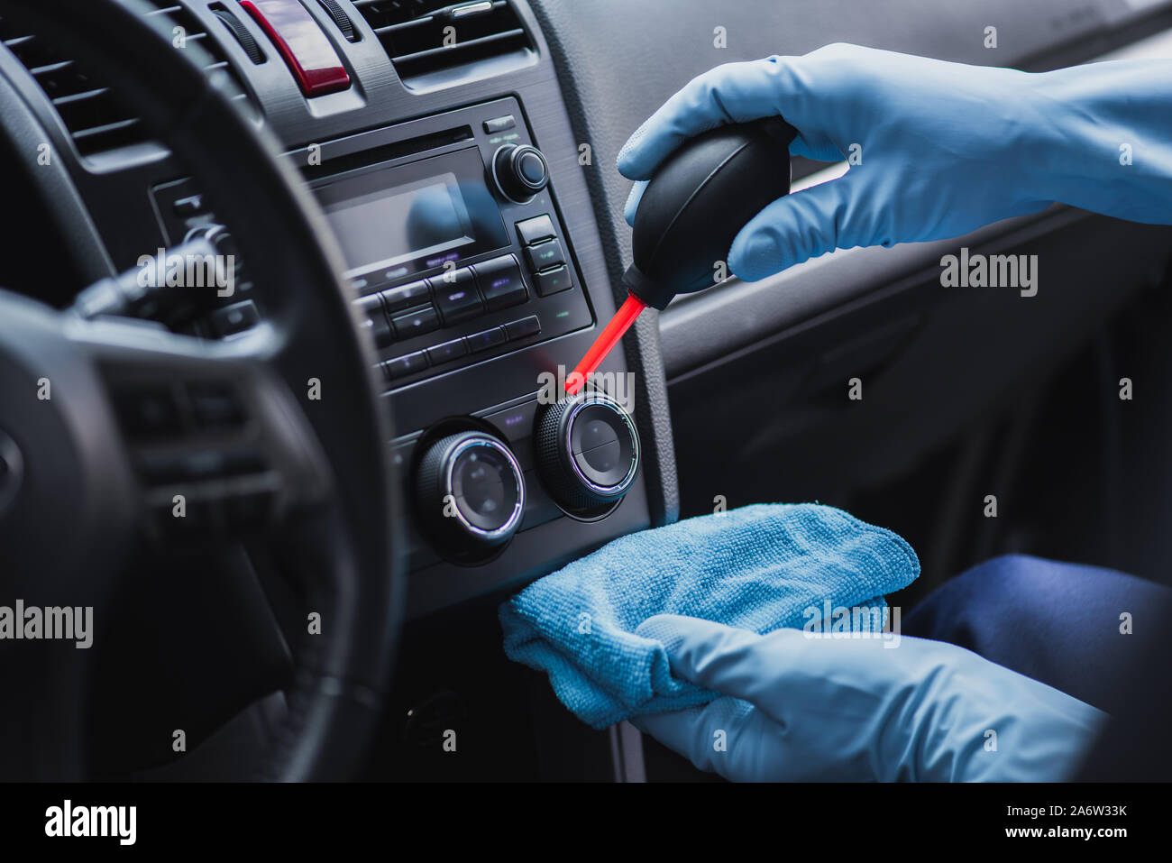 cropped view of car cleaner dusting dashboard with rubber air cleaner