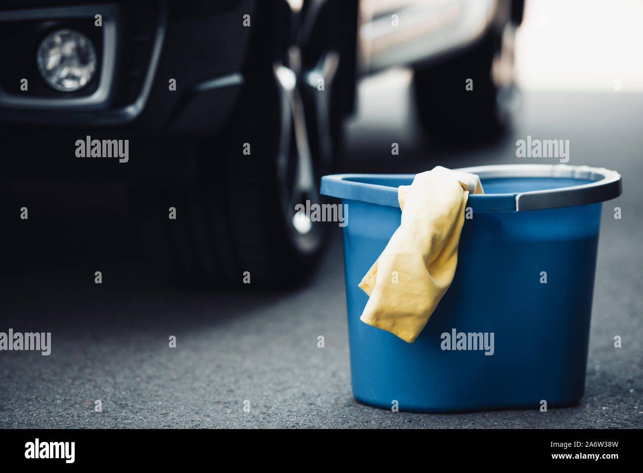 blue bucket and yellow rag on asphalt near black car Stock Photo - Alamy