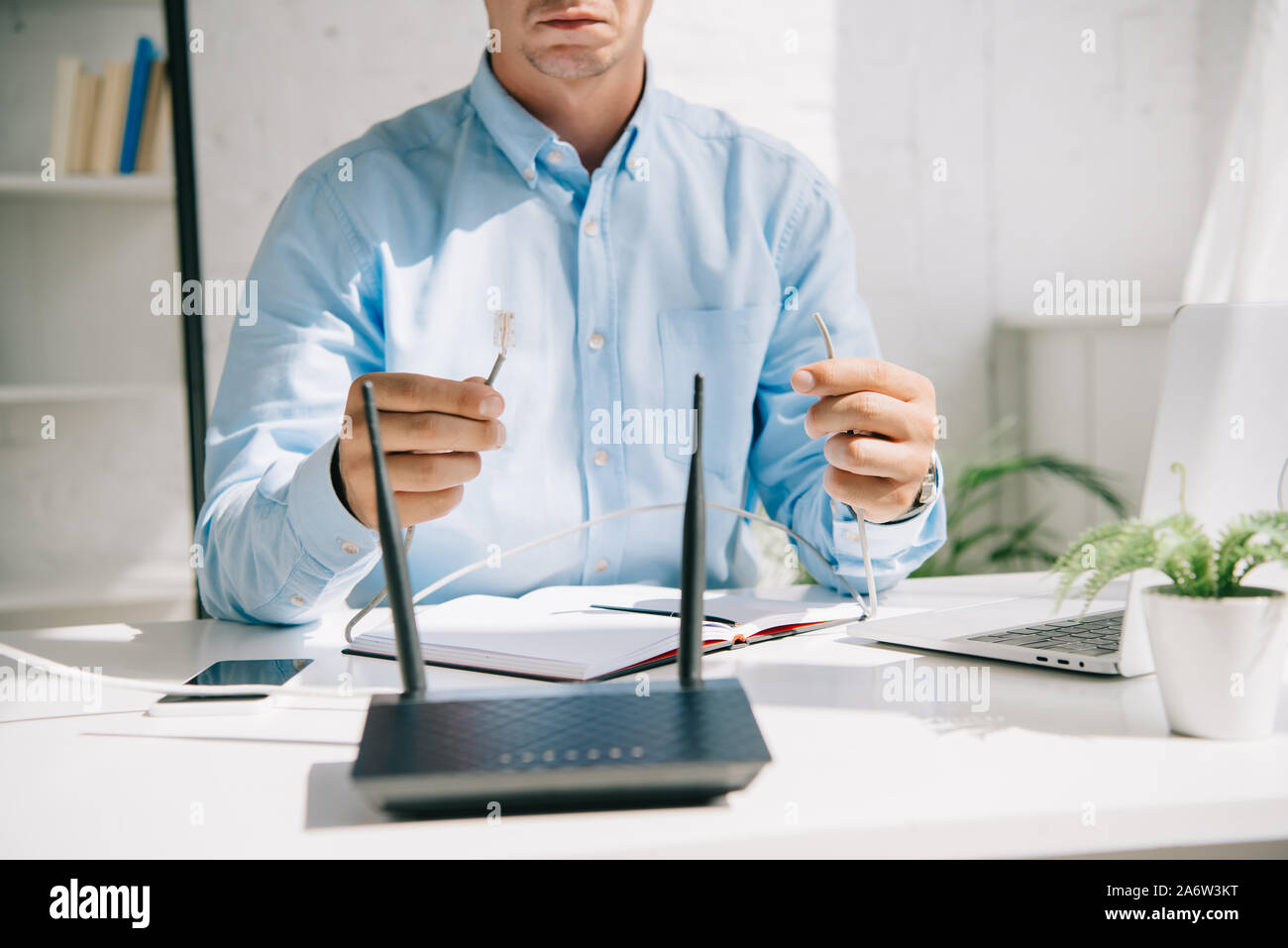 cropped view of businessman holding wires with connectors near router Stock Photo