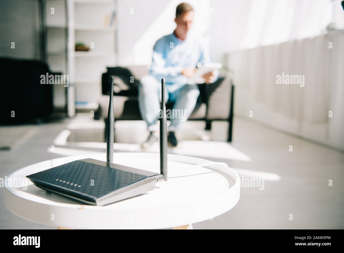 selective focus of black plugged router on white table and businessman ...