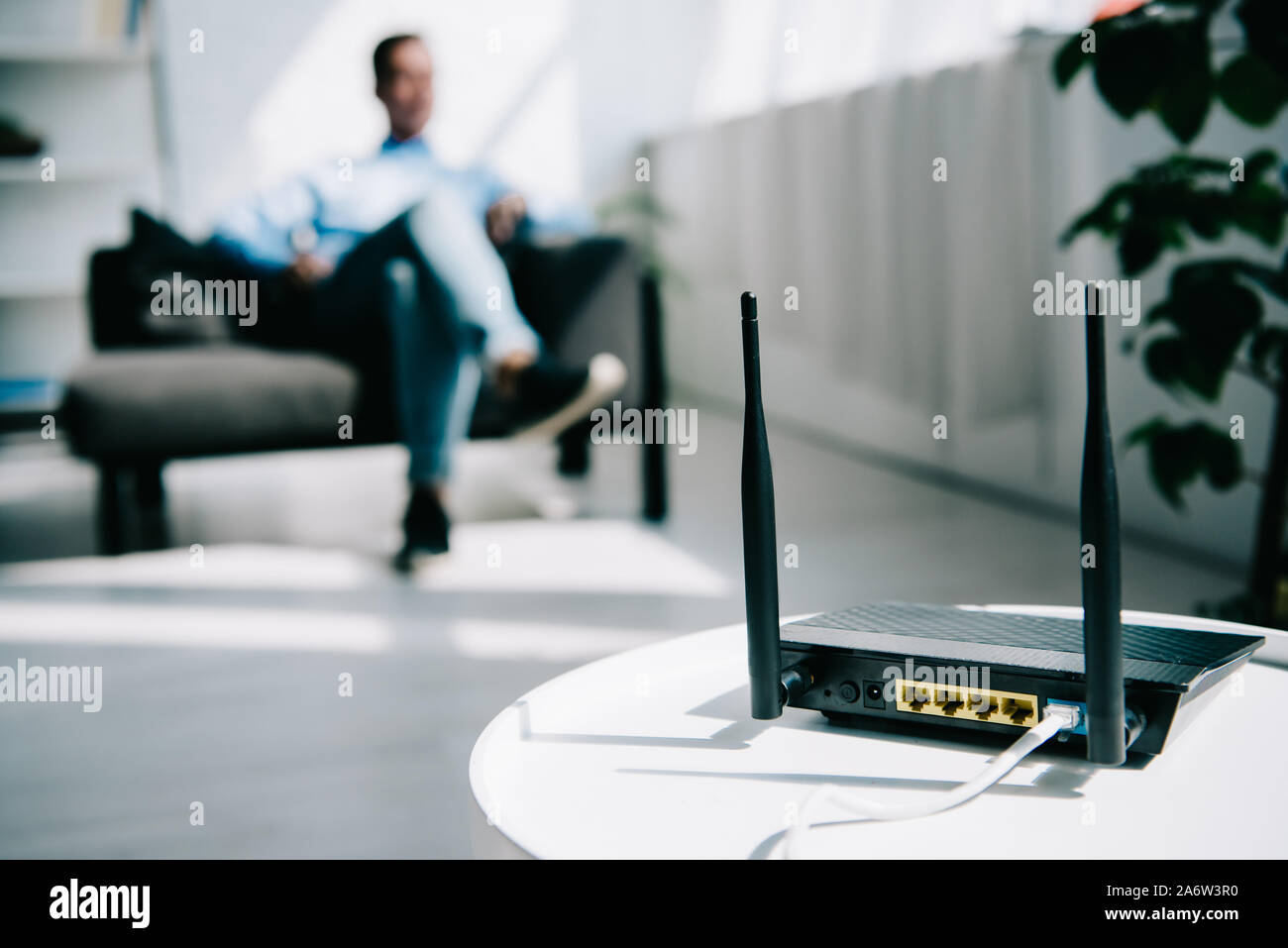 selective focus of black plugged router on white table and businessman ...