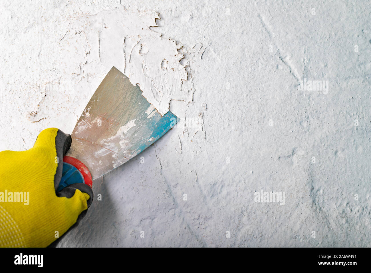 Removing old paint from the wall with a metal spatula. Small painting