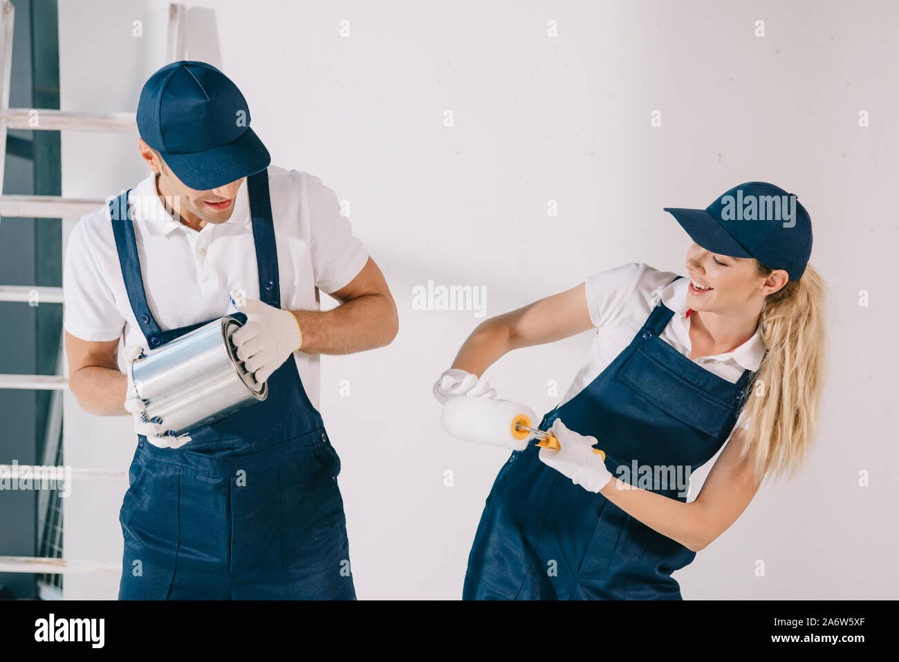 cheerful painters having fun while holding can with paint and paint roller Stock Photo