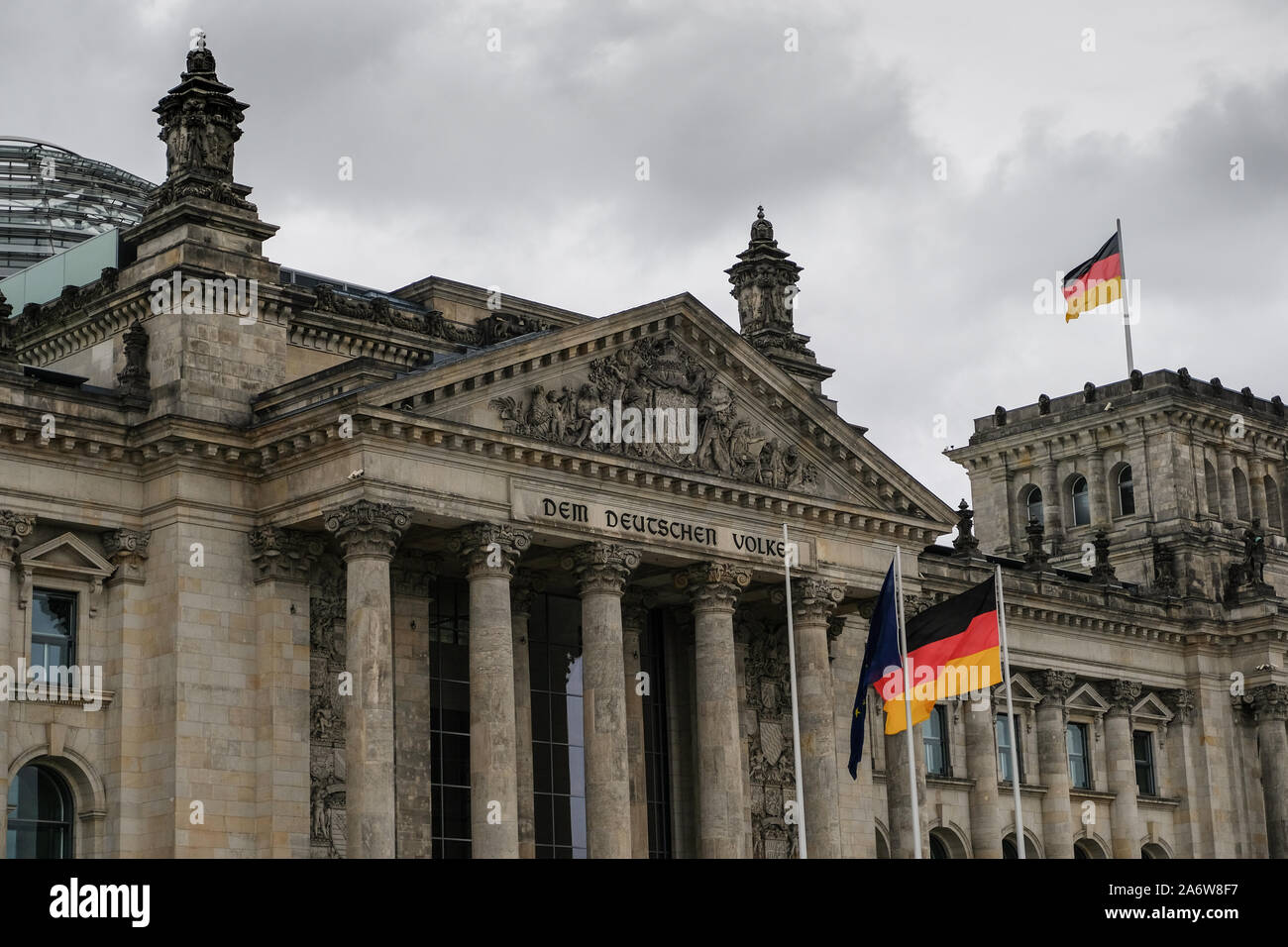 Berlin famous historic reichstag facade with german flags over cloudy sky,symbol Stock Photo