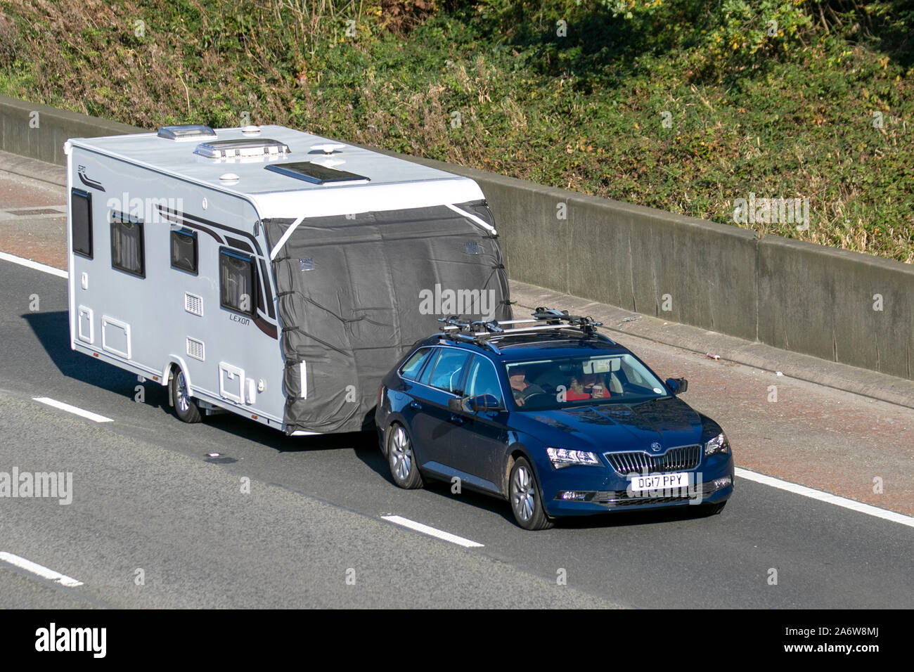 2017 BLUE Škoda Superb SE TDI towing caravan; UK Vehicular traffic, transport, modern vehicles, saloon cars, south-bound on the 3 lane M6 motorway highway. Stock Photo