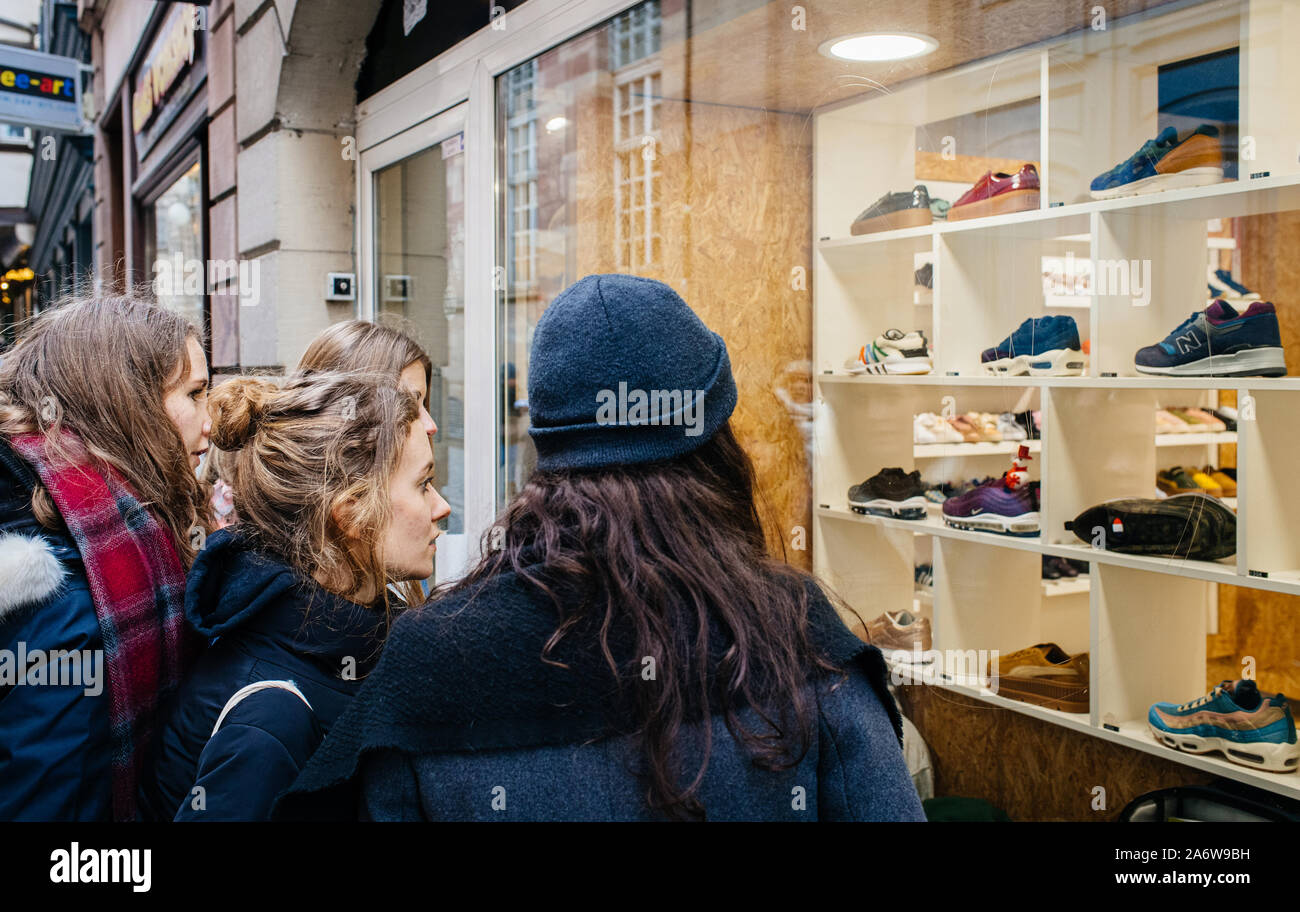 Strasbourg, France - Dec 27, 2017: Group of young female women admiring the  showcase window of a shoe store in central part of the city Nike, New  Balance, Salomon brands for sale
