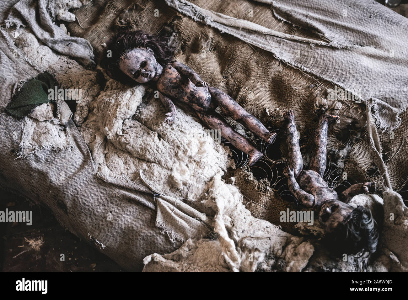 top view of scary and burnt baby dolls on damaged bed, post apocalyptic concept Stock Photo