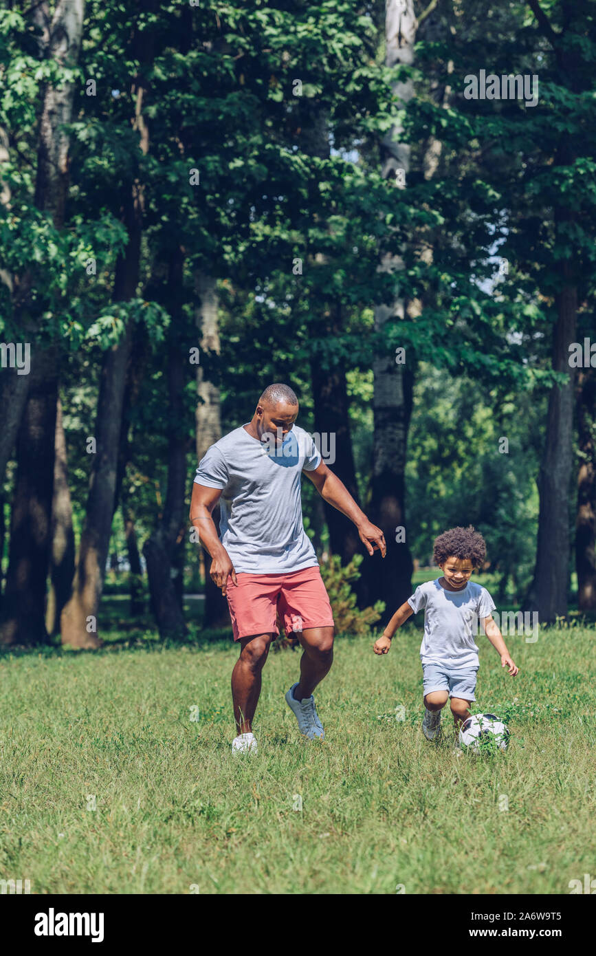 happy african american father and son playing football in park Stock ...