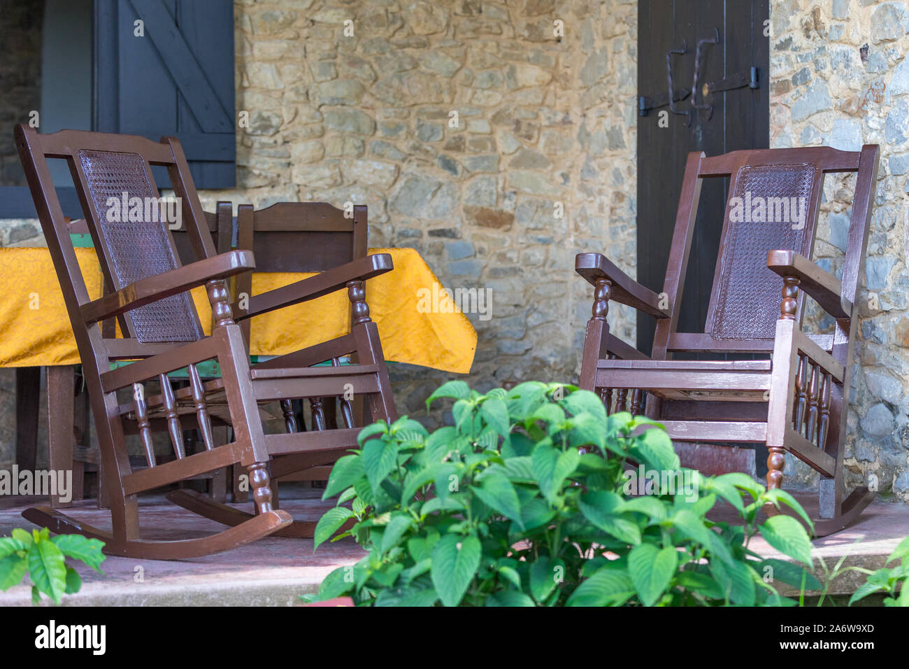 Typical Cuban veranda with brown wooden rocking chairs and stone facade Stock Photo